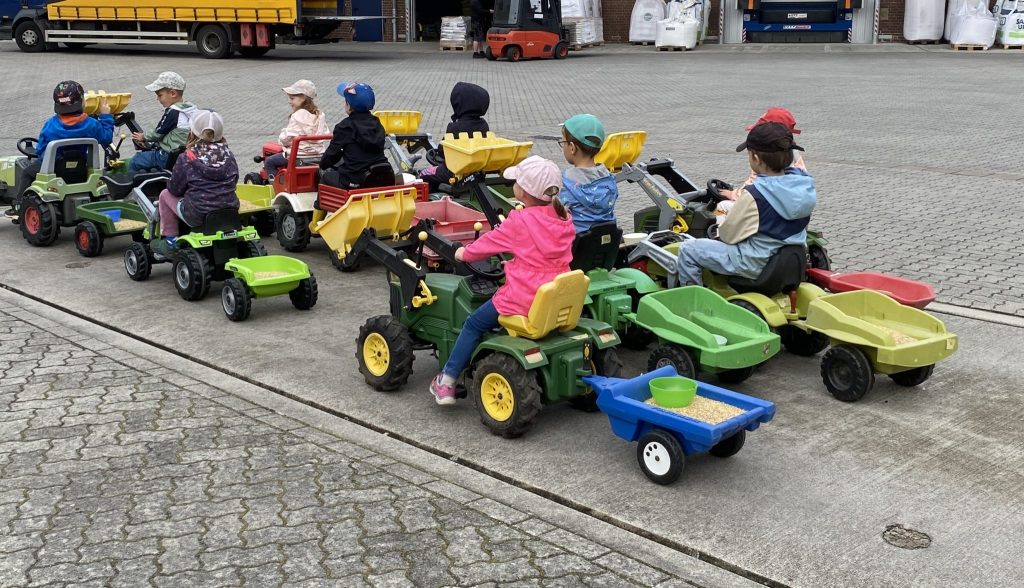Kindergartenkinder auf Spielzeug Treckern